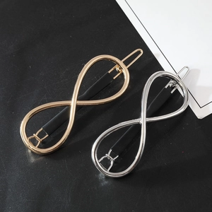 Close-up of polished infinity symbol hairpins in gold and silver finish on black