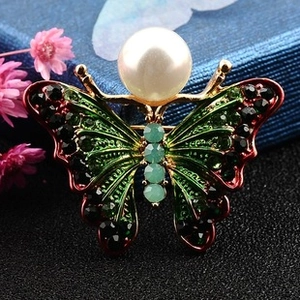 Macro shot of elegant butterfly brooch with green crystals and white pearl detail