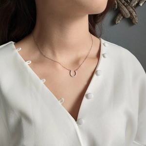 Detailed view of a silver horseshoe pendant necklace with sparkling pavé crystals on a model