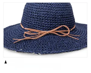 Detail of dark blue woven straw hat featuring a brown string bow and fine texture