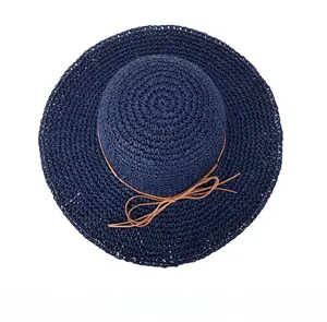 Top down view of a navy blue hand-woven straw sun hat with brown ribbon and wide brim