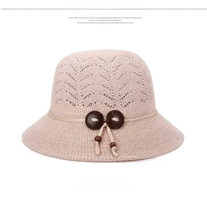Detail of beige knitted sun hat with wooden buttons and decorative beaded rope knot