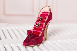 Macro shot of red silk high heel jewelry holder with owl rings and golden bead trim