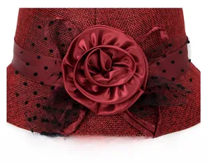 Detail of burgundy linen sun hat featuring a large satin rose and black polka dot mesh