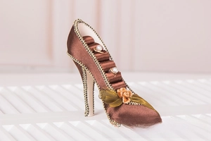 Detail of high heel jewelry stand in brown satin with gold trim and pearl ring slots