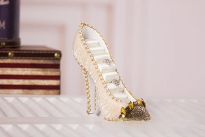 Close-up of champagne gold high heel ring holder with rhinestone trim and satin slots