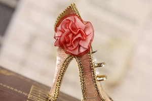 Detail of champagne high heel jewelry stand with red chiffon flower and gold chain