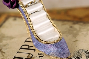 Detail of high heel ring holder with purple fabric, gold lace and rose flower decor