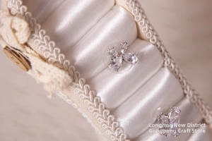 Detailed close-up of silver flower stud earrings with white cubic zirconia on satin