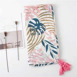 Détail d'une écharpe bohème à imprimé floral avec glands roses et feuilles tropicales