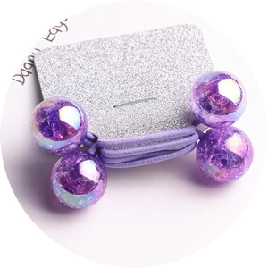 Detailed macro view of two purple iridescent beaded hair ties on a glitter card display