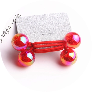 Detail of red elastic hair bands featuring iridescent translucent beads on a card