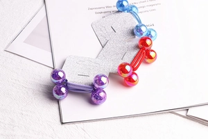 Close-up of colorful iridescent bubble beads on elastic hair ties in blue, red and purple