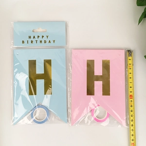 Detail of pink and blue swallowtail birthday banners with gold foil H letter and ribbon