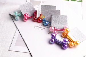Close-up of colorful sparkling bead hair ties on silver cards with natural leaf decor