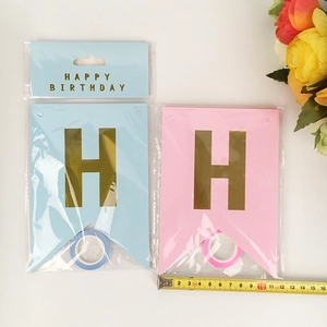Detail of pink and blue Happy Birthday banners with gold letters and measurement tape