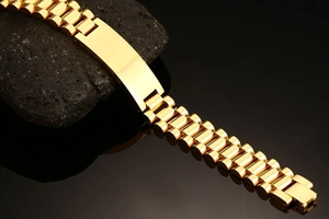 Close-up of golden stainless steel link bracelet with engravable plate on black rock