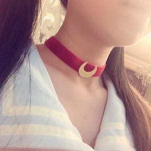 Red velvet choker necklace with a gold crescent moon pendant worn by a model