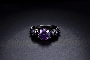 Macro shot of black skull ring featuring a large purple zircon with gothic detailing