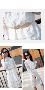 Detailed view of golden leaf buckle on a white lace dress with elastic waist design