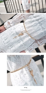 Detail of golden metal leaf belt with sparkling fox pendant on white lace dress