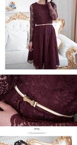 Detail of burgundy lace dress featuring floral patterns and a slim gold bow belt