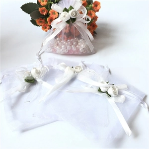 Detailed view of white organza drawstring gift bag with elegant fabric rose floral decoration