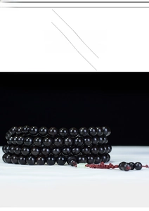Detail view of 108 ebony wood prayer beads with red tassel and green accent bead