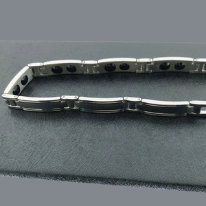 Bracciale magnetico in acciaio inossidabile lucido per coppie su sfondo di pelle nera