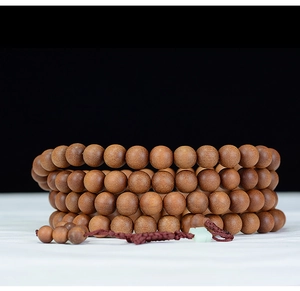 Macro shot of 108 sandalwood prayer beads with natural textures and green accent beads