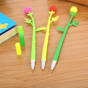 Three creative artificial rose-shaped pens in pink, red and yellow on a wooden desk
