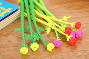 Detail of rose flower pens in red, pink, and yellow on a wooden desk setting