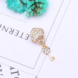 Detailed close-up of golden heart lock and key charm with sparkling white zircon pavé