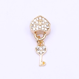 Detailed close-up of gold heart lock and key charm with sparkling pavé zircons