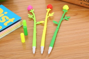 Detailed close-up of rose flower shaped gel pens in pink, red, and yellow on a wooden desk