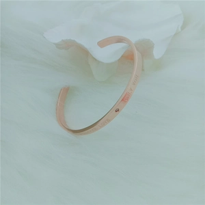 Detail of rose gold C-shaped bangle featuring Forever Love engraving and small diamond