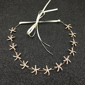 Detail of bridal headband with golden starfish rhinestones and cream ribbon tie