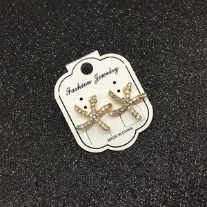 Detailed close-up of gold starfish earrings with sparkling rhinestones on jewelry card