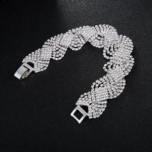 Detail of wide wave-shaped silver bracelet with dense rhinestones and square buckle