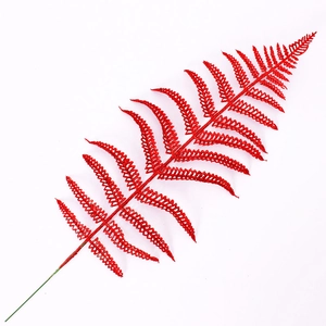 Macro detail of red artificial fern leaf with sparkling gold glitter for Christmas decor