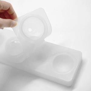 Macro shot showing the two-piece white silicone spherical mold being opened by hand