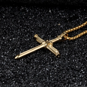 Macro shot of gold cross necklace with unique knot design and high-polish box chain finish