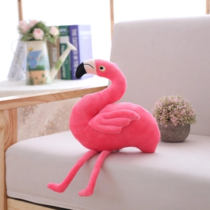 Cute pink flamingo plush toy pillow with long legs sitting on a sofa for home decor