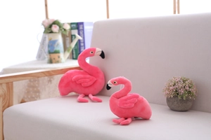 Close-up of pink flamingo plush toy duo in various sizes on a light fabric sofa