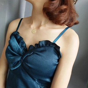 Close-up of minimalist gold circular face pendant necklace on model with silk dress