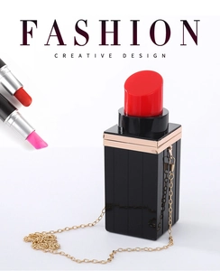 Detail of creative lipstick shaped evening bag with glossy black body and gold chain