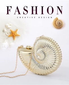 Detail of golden nautilus shell clutch bag with metallic chain on beach-themed background
