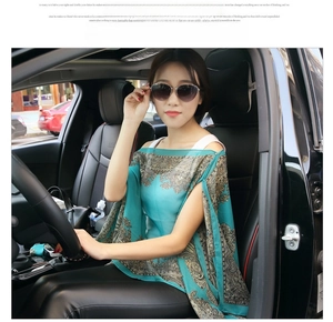 Detail of silk-like paisley print shawl with cold shoulder design in peacock green color