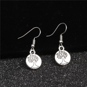 Macro di orecchini albero della vita in argento con gancio su uno sfondo scuro materico