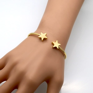Detailed view of a gold-plated open star bracelet on a model's wrist for styling